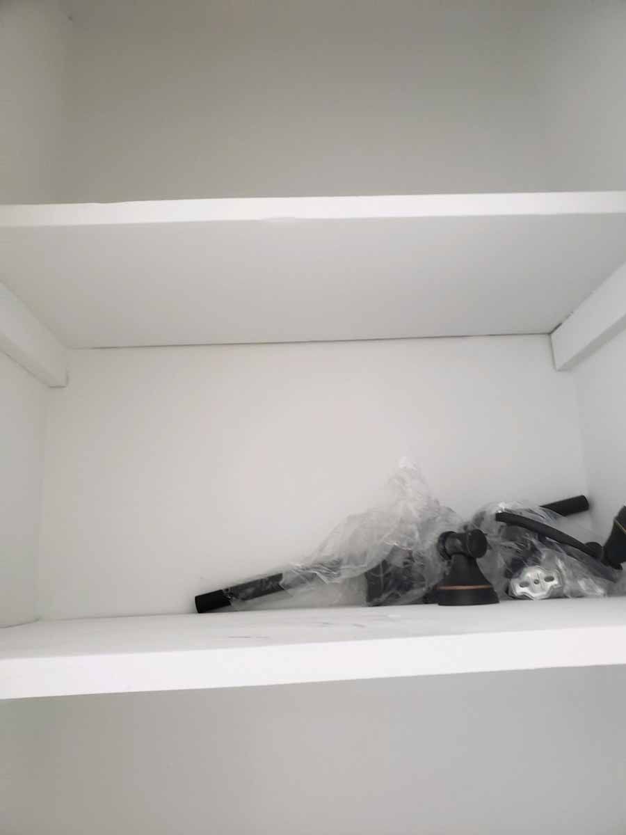 White empty cabinet shelves with a plastic-wrapped object in the lower shelf.