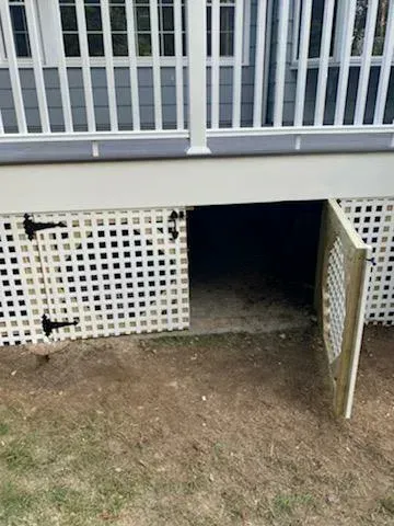 White latticework covers the underside of a deck with an open door revealing dark storage space.