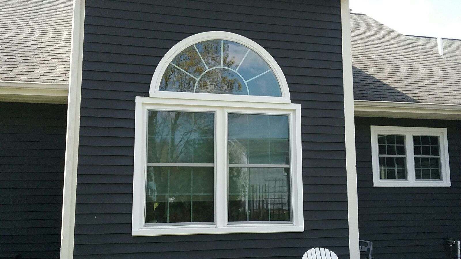 Dark blue house siding with a large arched window and a smaller window on the right.