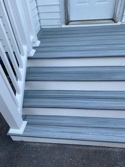 Gray steps with white risers and railing leading to a white door.
