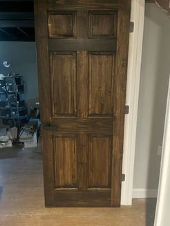 Wooden interior door, stained dark brown, with panel detailing, set in a white door frame.