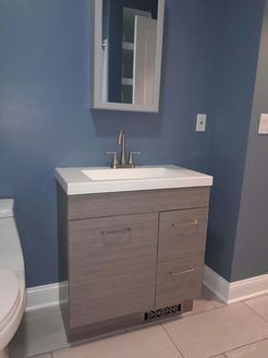 Bathroom with grey vanity, white countertop, silver faucet, and blue walls.