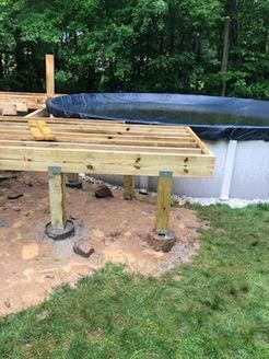 Partially built wooden deck next to an above-ground pool; construction site.