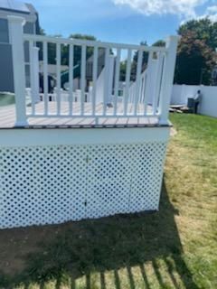 White deck with lattice skirting, balustrade railing, and a person in the background.
