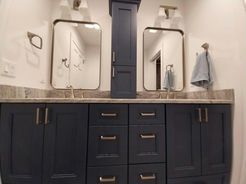 Blue double bathroom vanity with two mirrors and a tall cabinet.