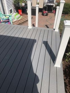 Gray composite deck with white posts; sunny outdoor setting.