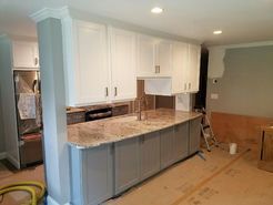 Kitchen with white upper cabinets, gray lower cabinets, granite countertop, and stainless steel appliances.