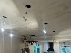 Ceiling with recessed lights, unfinished, with chandelier, and partially visible person.