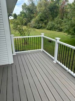 Gray deck with white railing, black spindles, and a grassy backyard.