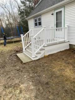 White deck and stairs attached to a house with a person standing nearby.