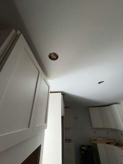 White kitchen cabinets, ceiling with recessed lighting hole.