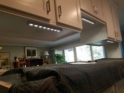 Bright under-cabinet lights illuminating a kitchen counter and cabinets. Interior with neutral colors.