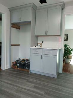 Light gray kitchen cabinets being installed; wood-look flooring.
