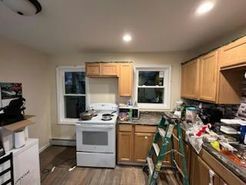 Kitchen with stove, cabinets, windows, and construction materials.