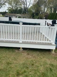 White deck with railing, person in dark clothing, in grassy yard.