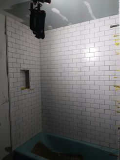 Bathroom with white subway tile walls, a blue tub, and a built-in shelf.