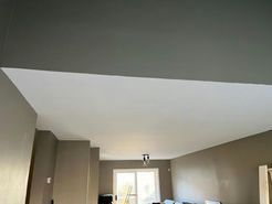 White and gray painted ceiling in a room with a doorway and a light fixture.