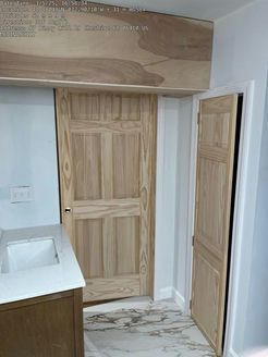 Bathroom with light wood doors, a white sink, and marble flooring.