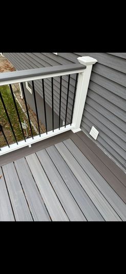 Gray composite deck with black metal railing and white trim. Gray siding is adjacent.
