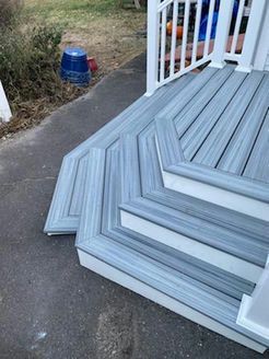 Gray and white composite deck steps leading up to a porch with white railing.
