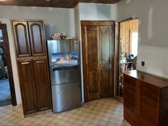 Kitchen interior with wood cabinets, stainless steel refrigerator, and wood-paneled doors, neutral-toned floor.