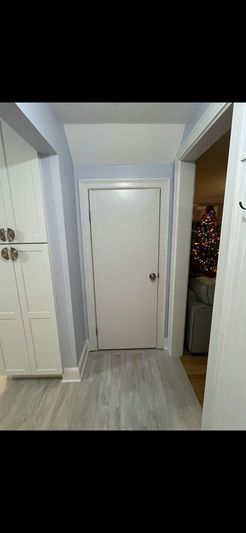 Hallway with white door, cabinets, and light gray flooring. The door is centered. A Christmas tree is visible.