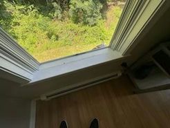 View from an open skylight with a grassy outdoor area. A light-colored trim and a small heater below.