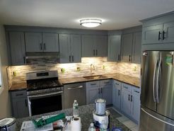 Gray kitchen cabinets, stainless steel appliances, granite countertops, and under-cabinet lighting.