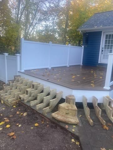 Partially built deck with white fence, brown wood steps, and blue house.