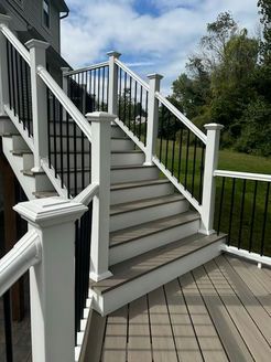 Outdoor staircase with white posts, dark railings, and gray steps.