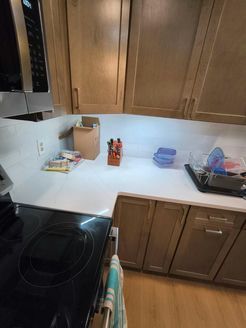 Kitchen countertop with upper and lower wood cabinets, a microwave, and a stovetop.