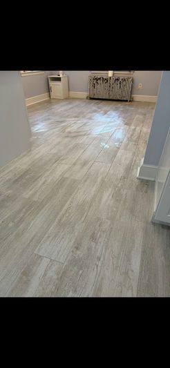 Wooden floors in a room with light gray walls, a radiator, and a small appliance.