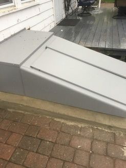 Gray ramp leading up to a wooden deck, next to a brick patio.