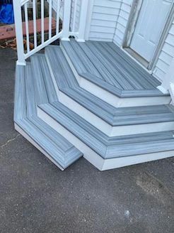 Gray composite deck stairs with white trim leading to a white door.