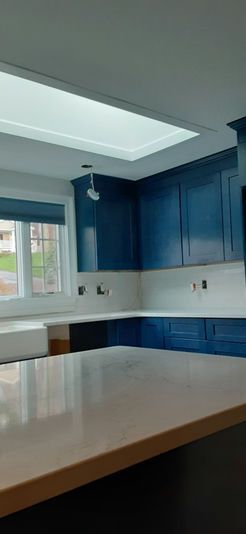 Kitchen with blue cabinets, white countertops, and a skylight.