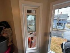 A tall, narrow window with broken glass, revealing a street scene and a red interior.