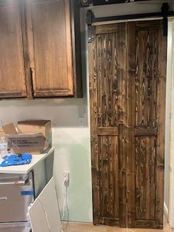 Dark stained wood sliding barn doors. Cabinet and countertop in view.