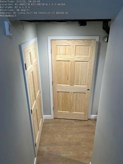 Hallway with two light wood doors, one open. Gray walls, light wood floor.