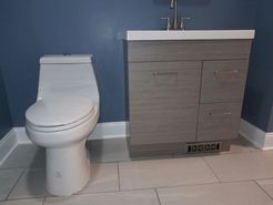White toilet and gray vanity in a modern bathroom with blue walls and tiled floor.