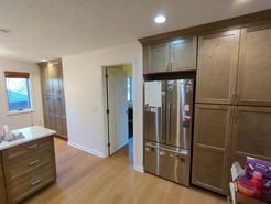 Kitchen with light wood cabinets, stainless steel refrigerator, and a small island with a countertop.