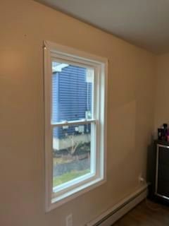 White-framed window on a tan wall; view of a blue-sided house outside.