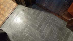Herringbone gray tile floor meets wood and another tile pattern.
