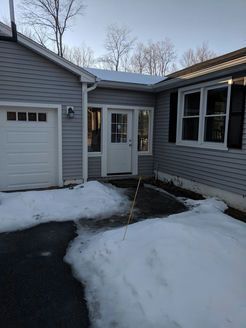 House exterior with snow and ice on the driveway, and a white door in the center.