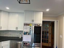 White kitchen cabinets above a stainless steel refrigerator with a doorway to the right.