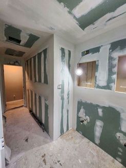 Interior room under construction, with drywall partially installed on walls and ceiling.