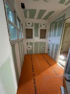 Bathroom under construction with green drywall, orange floor heating, and unfinished walls.