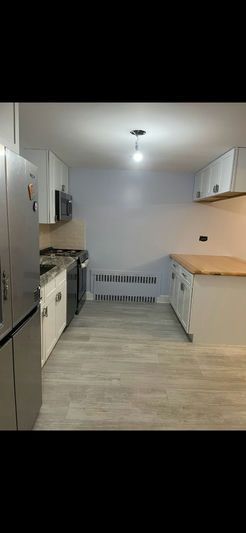 Kitchen with white cabinets, light gray flooring, and a stainless steel refrigerator.