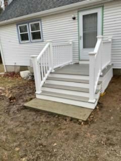 White deck with steps leading to a door; railing on either side. Brown yard.