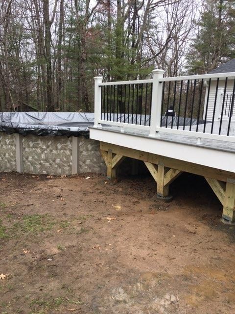 Wooden deck with black railing and above-ground pool in backyard.