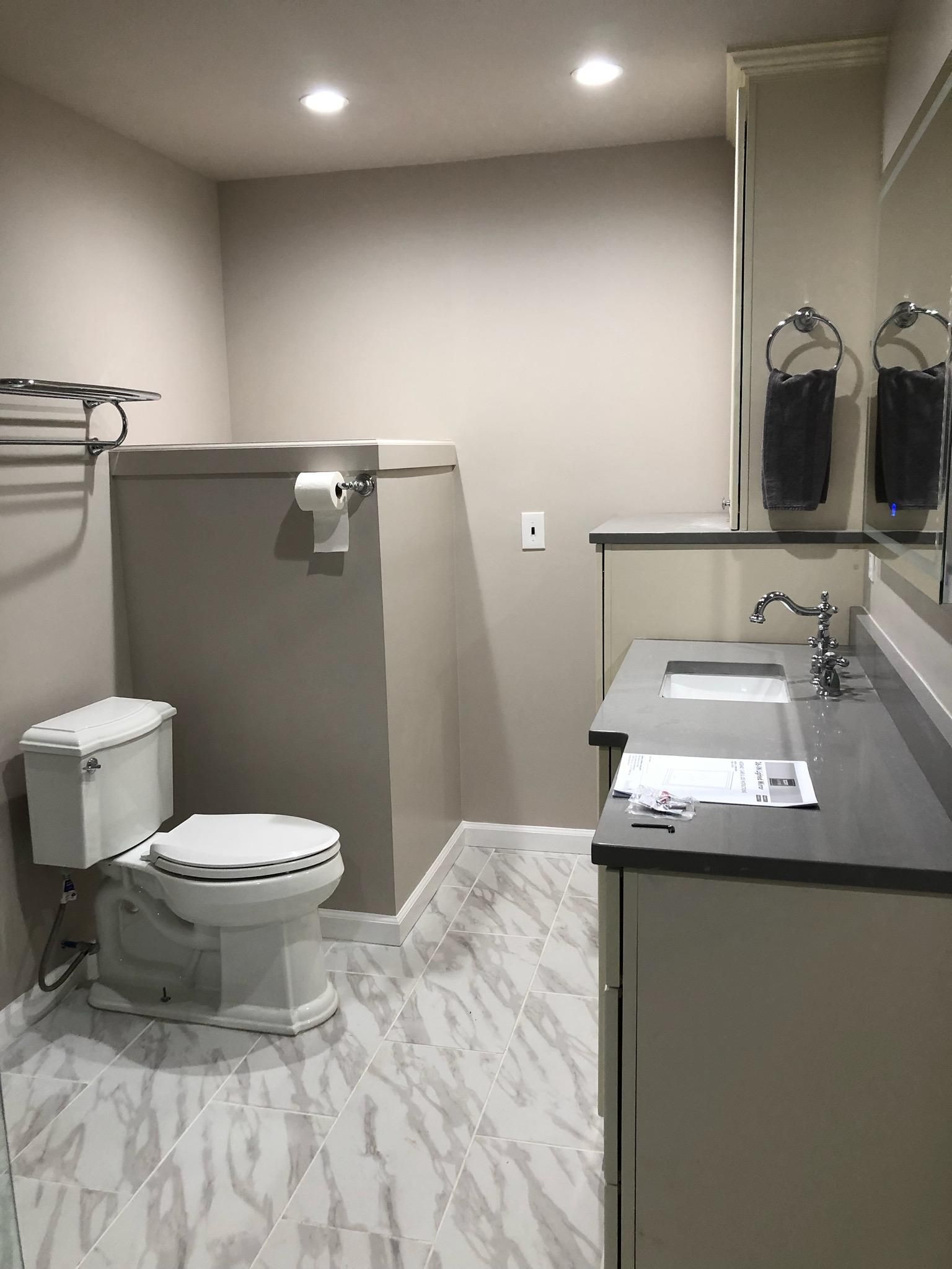 Bathroom with white tile floor, toilet, vanity, and a large box-like structure.